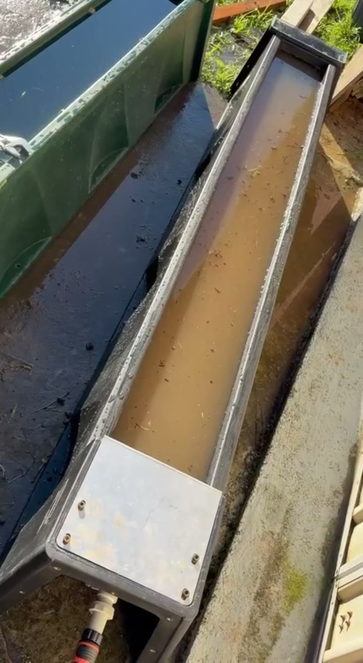 A trough with sediment and muddy water before flushing